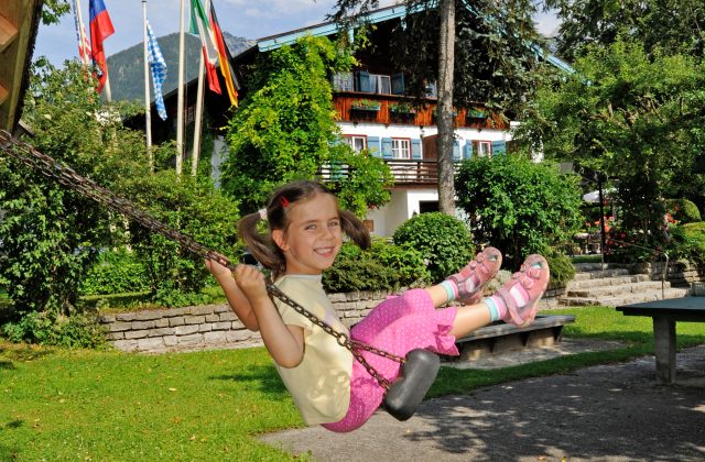 Les enfants se balancent sur l'aire de jeux du Stoll's Hotel Alpina à Schönau am Koenigssee / Berchtesgaden