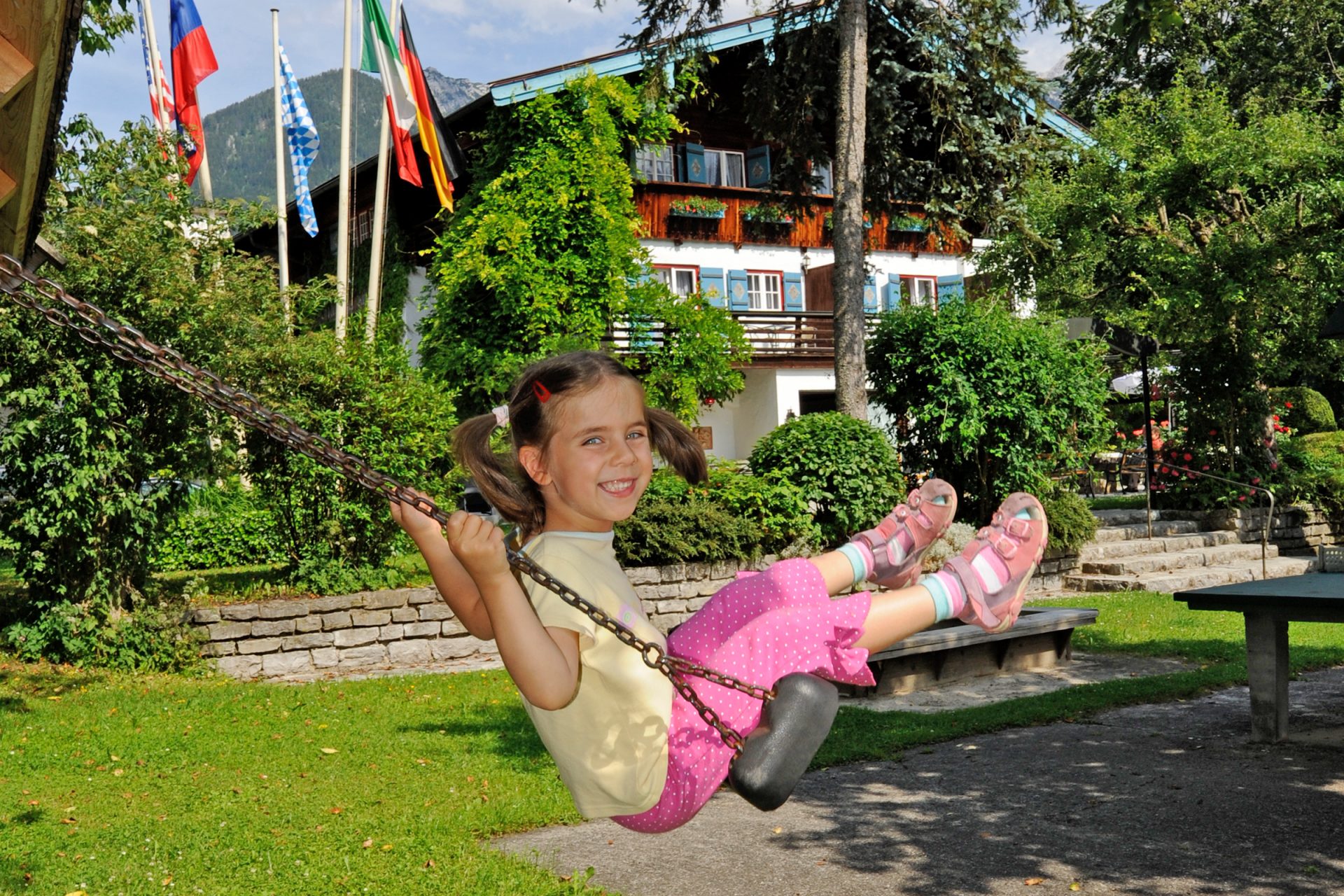 Les enfants se balancent sur l'aire de jeux du Stoll's Hotel Alpina à Schönau am Koenigssee / Berchtesgaden
